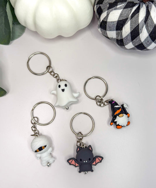 four keychains with different Halloween-themed designs, including a ghost, a mummy, a bat, and a gnome.