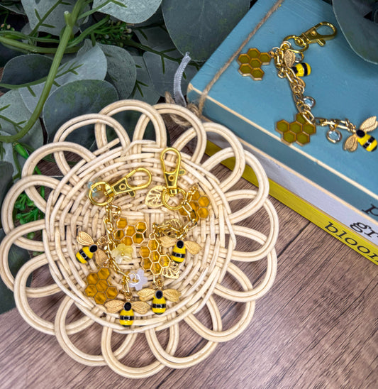 a wicker basket filled with various beaded and metal accessories, including a keychain and earrings, placed on a wooden surface next to a book.