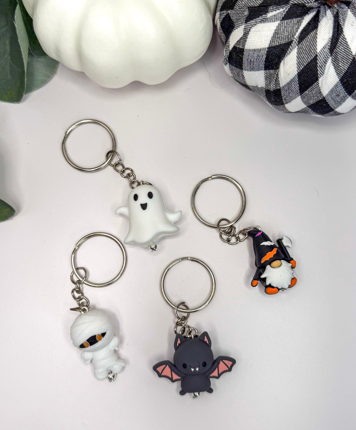 four keychains with different Halloween-themed designs, including a ghost, a mummy, a bat, and a gnome.