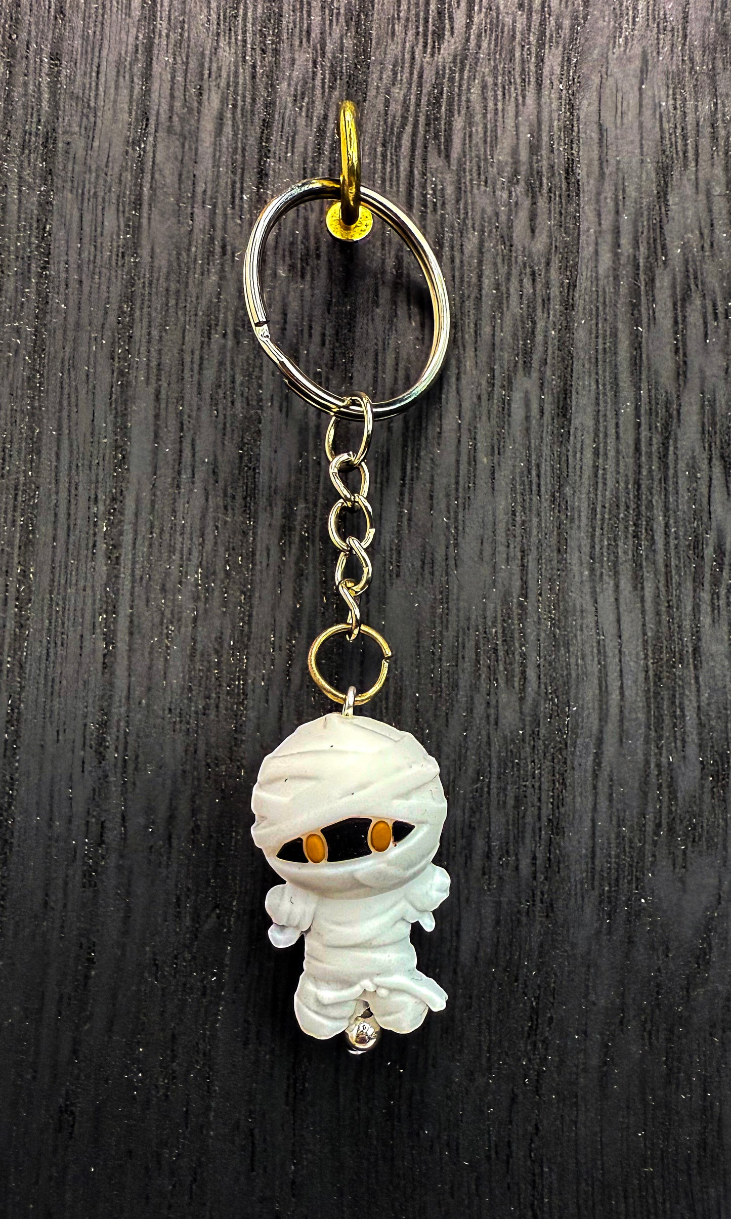 A keychain with a small white mummified figure attached to a metal ring.