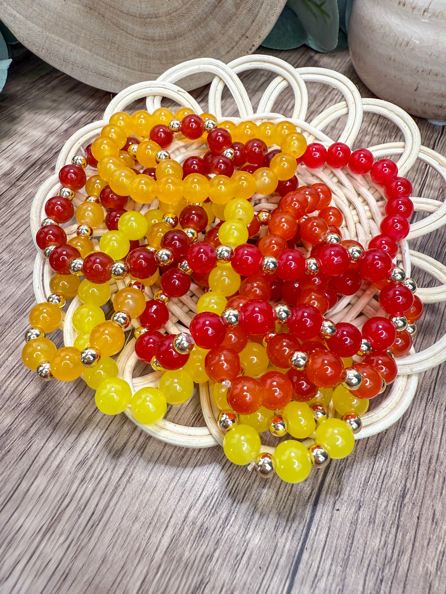 A wicker basket filled with colorful beaded bracelets in various shades of red, yellow, and orange.