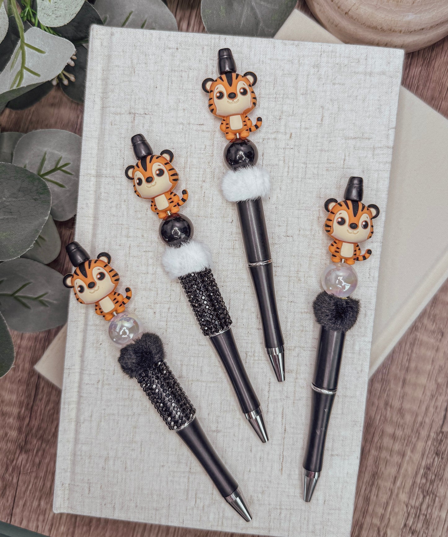 a collection of four pens with tiger-like designs on them, placed on a white surface.