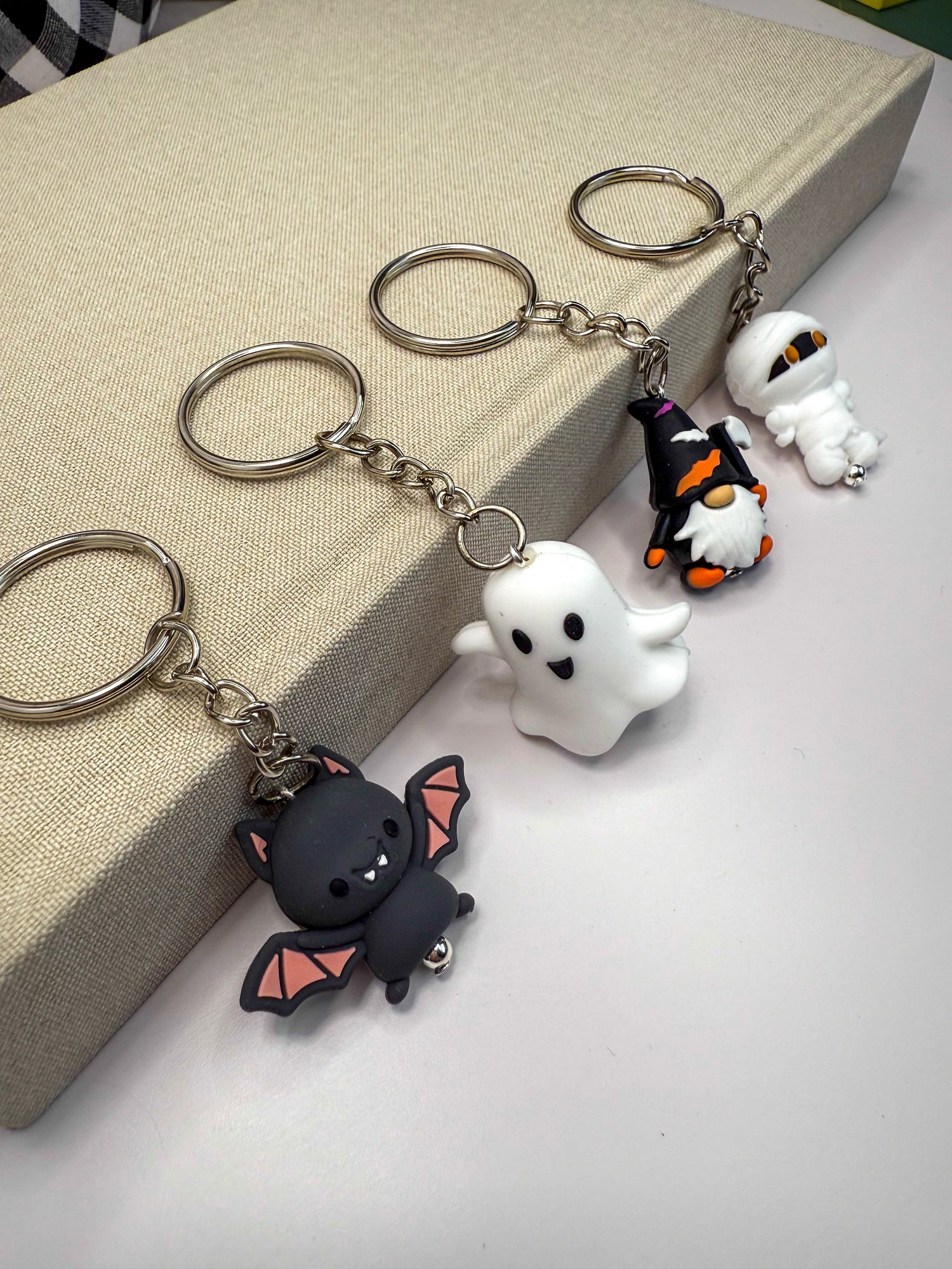 a collection of Halloween-themed keychains, including a bat, a ghost, a gnome, and a mummy.