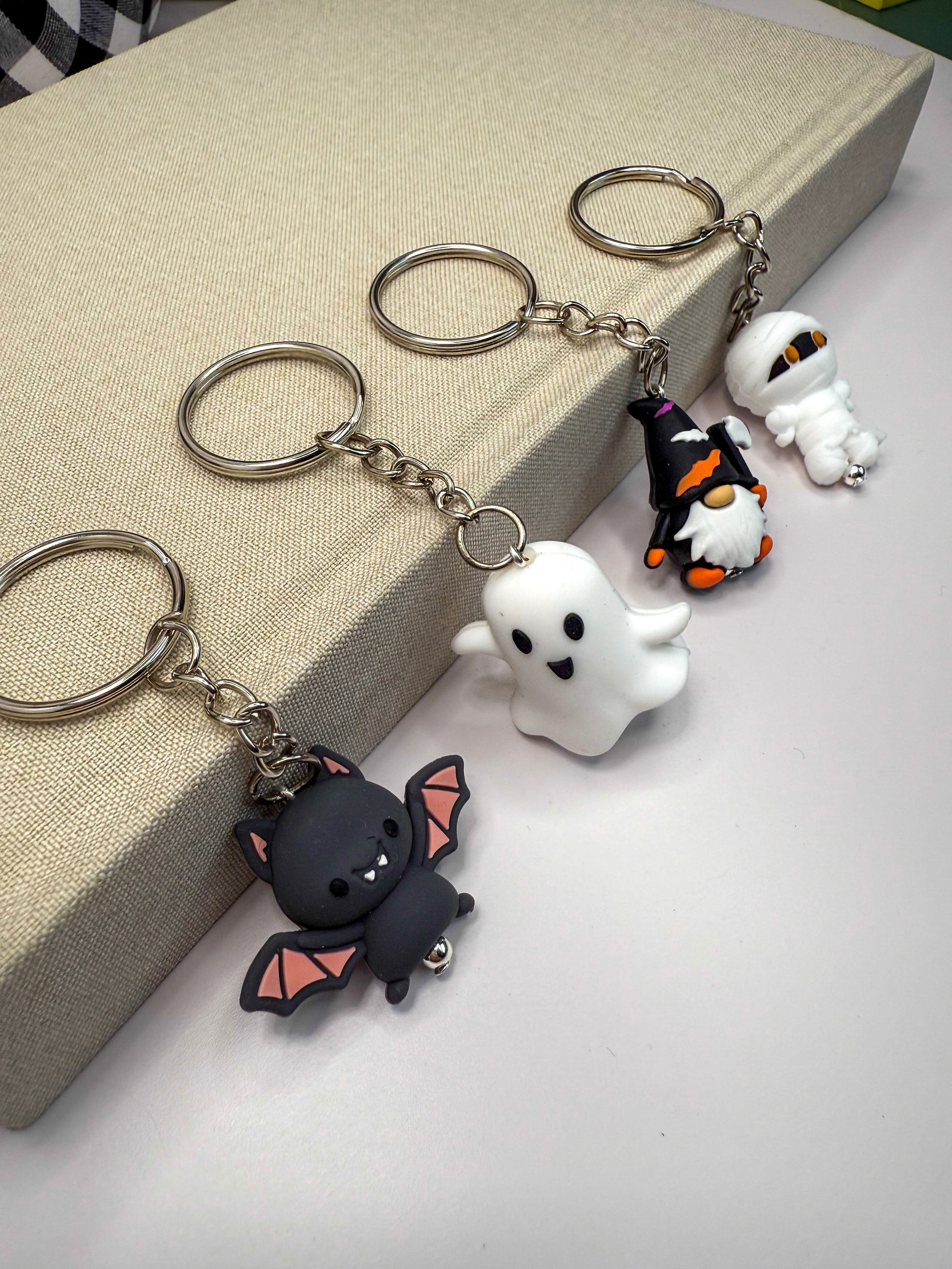 a collection of Halloween-themed keychains, including a bat, a ghost, a gnome, and a mummy.