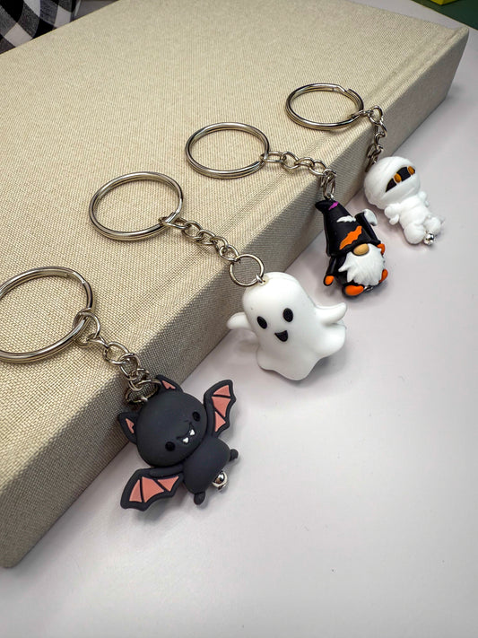 a collection of Halloween-themed keychains, including a bat, a ghost, a gnome, and a mummy.