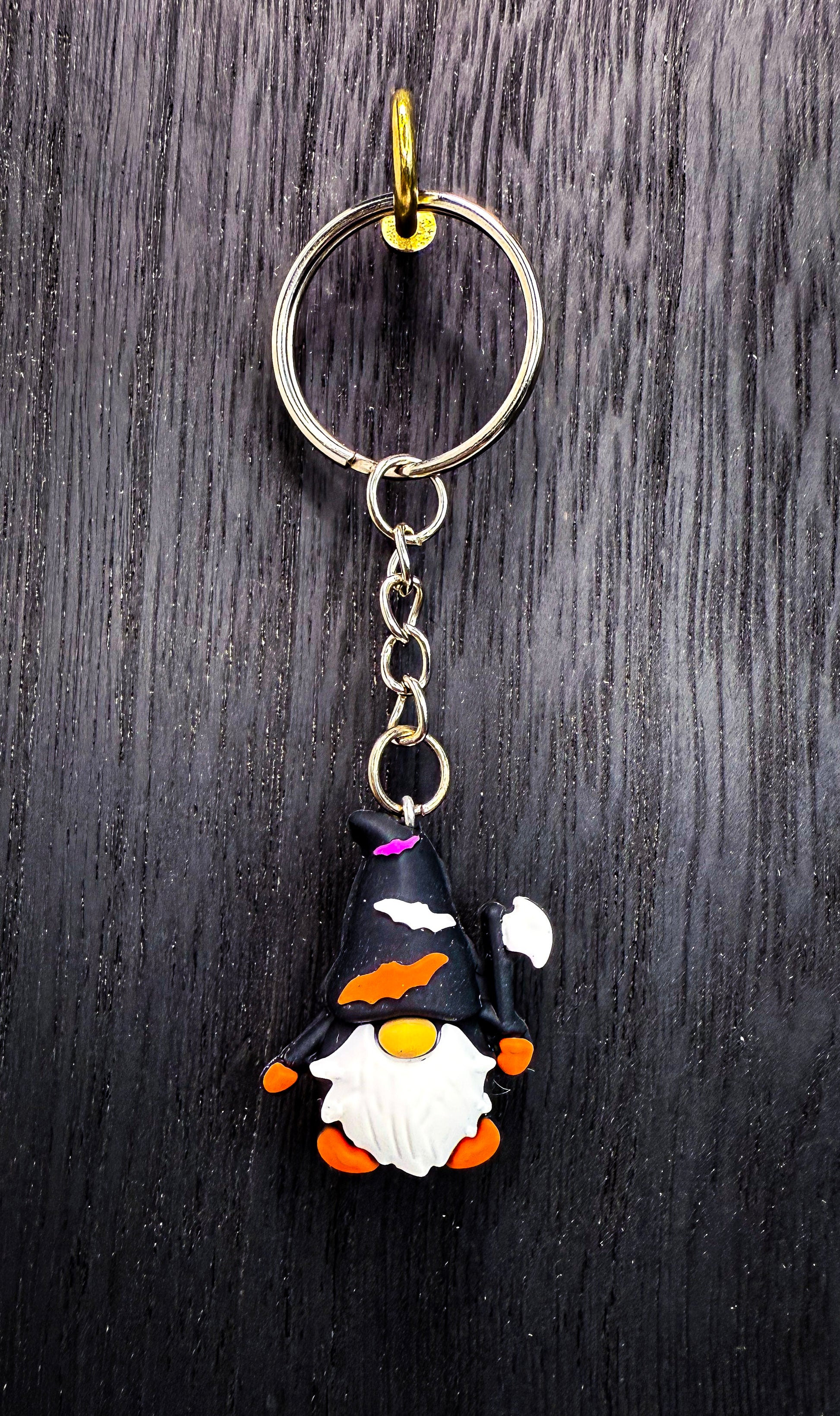 A keychain featuring a gnome-like character with a white beard and orange accents, hanging from a keyring.