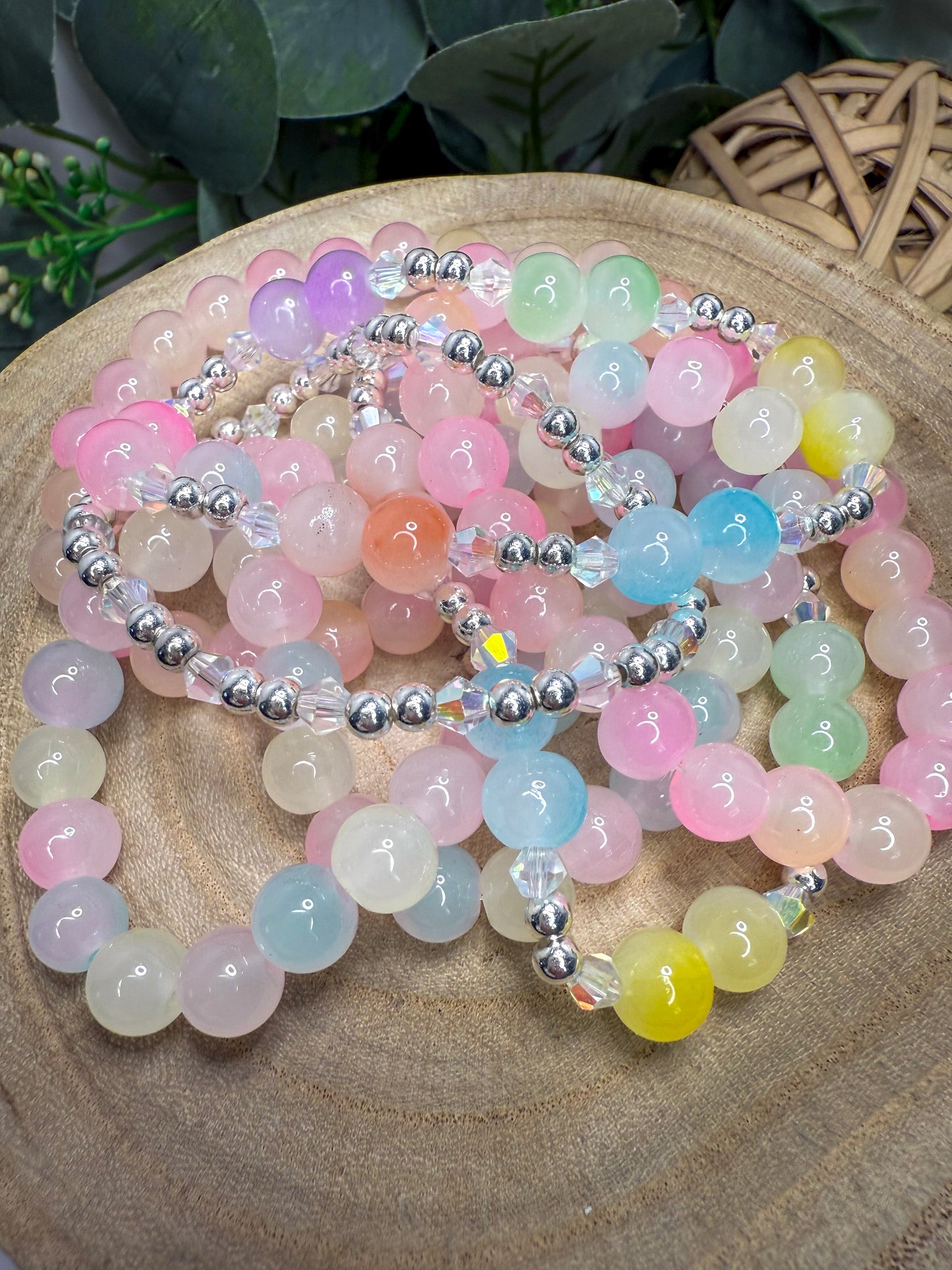 A collection of colorful beaded bracelets and necklaces arranged on a wooden surface, with a blurred natural background.