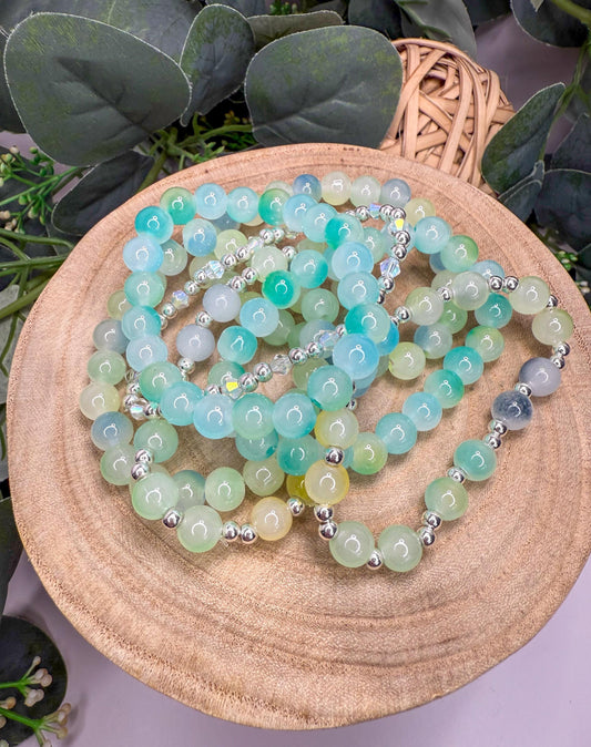 A collection of colorful beaded bracelets arranged on a wooden surface, with a wicker basket visible in the background.