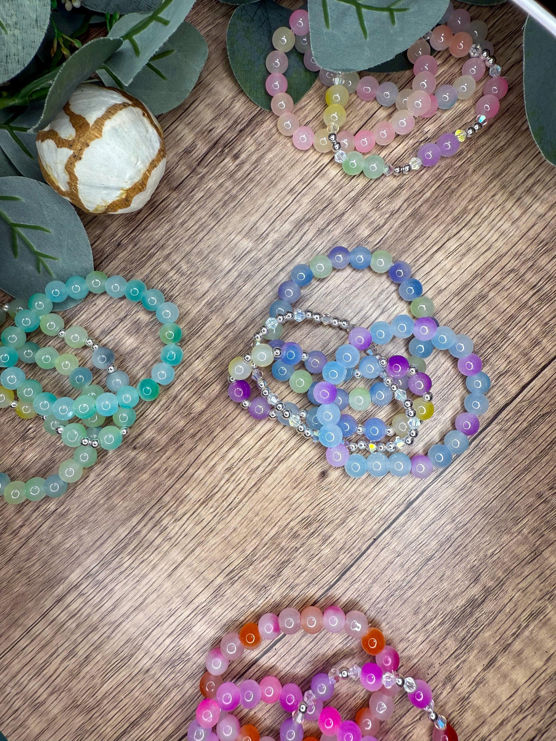 a collection of colorful beaded bracelets arranged on a wooden surface, with some of the bracelets overlapping each other.