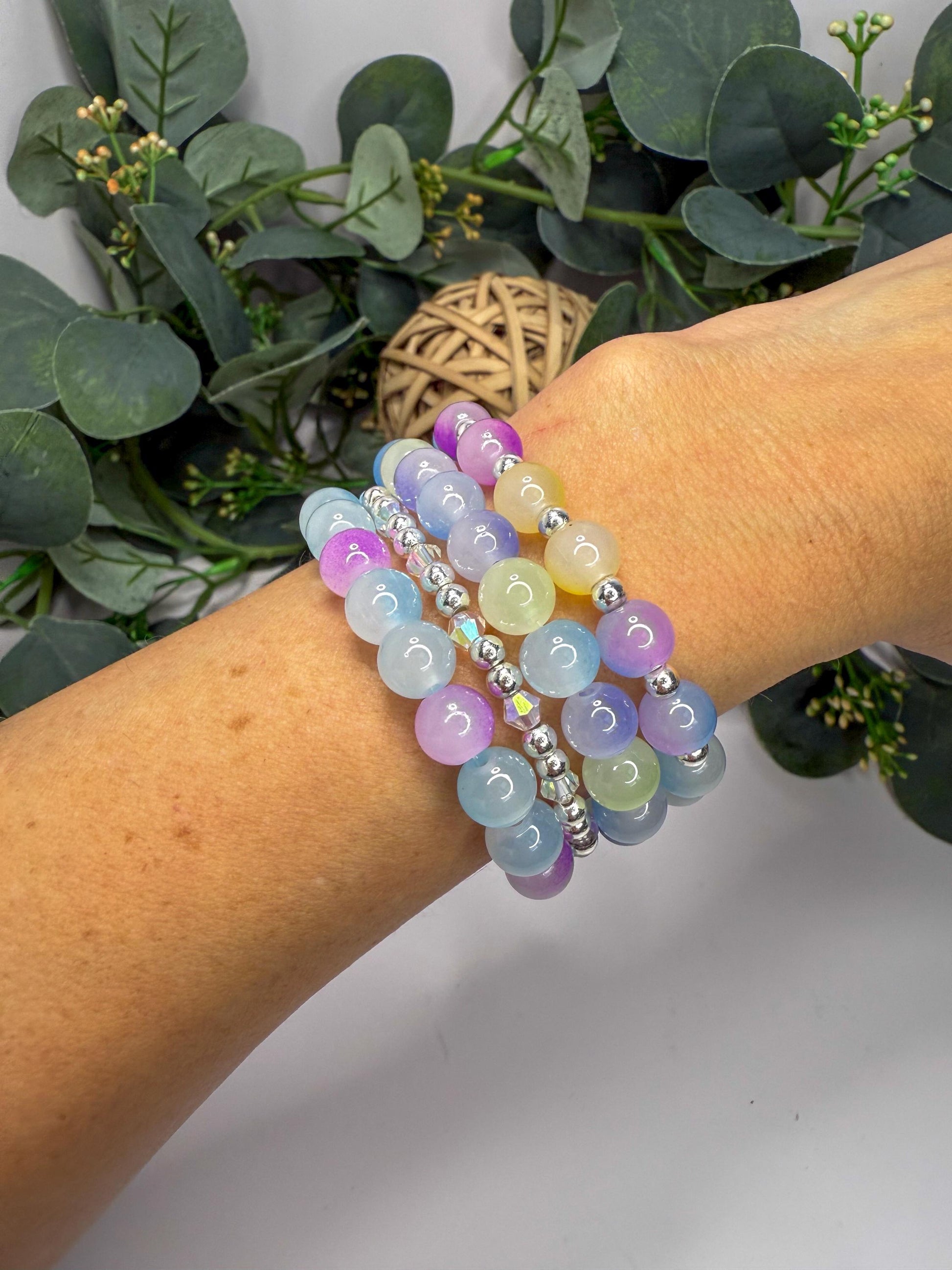 A person&#39;s wrist wearing a colorful beaded bracelet with various shades of blue, purple, and yellow beads.