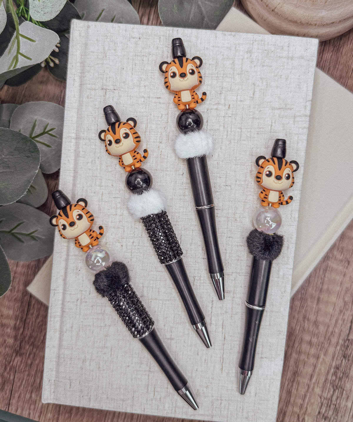 a collection of four pens with tiger-like designs on them, placed on a white surface.
