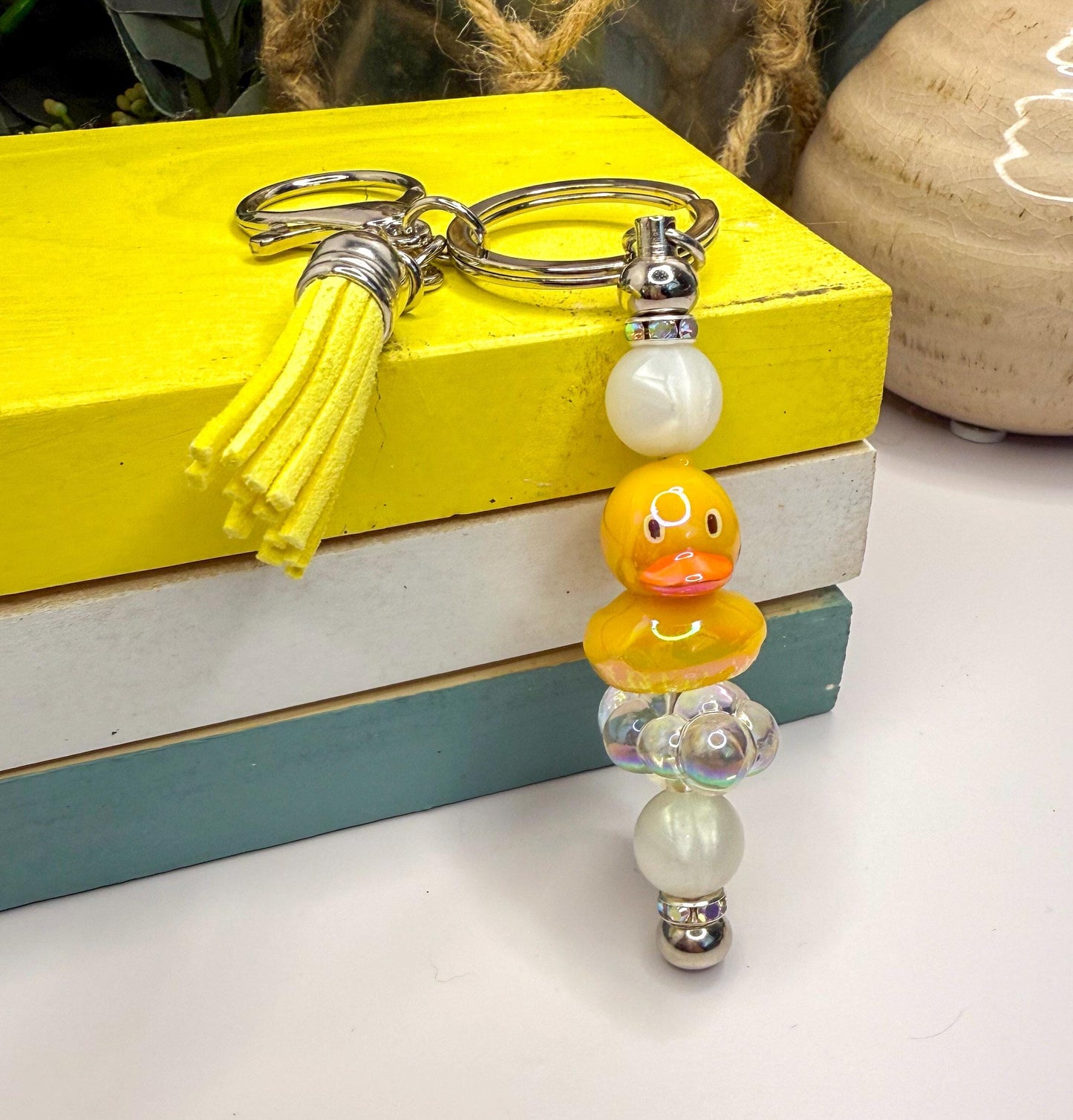 A yellow keychain with a tassel and a keyring is placed on top of a stack of books.