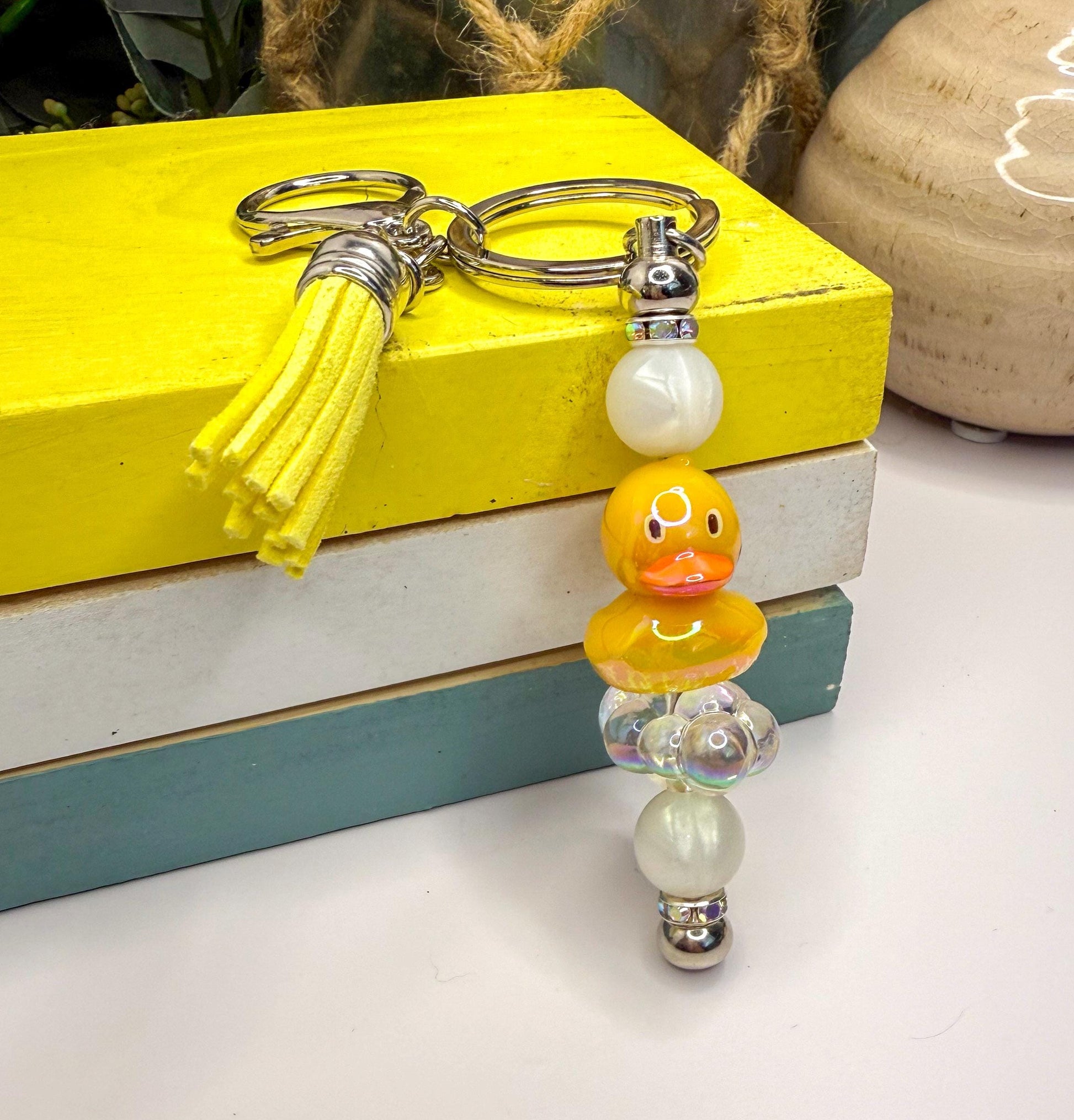 A yellow keychain with a tassel and a keyring is placed on top of a stack of books.