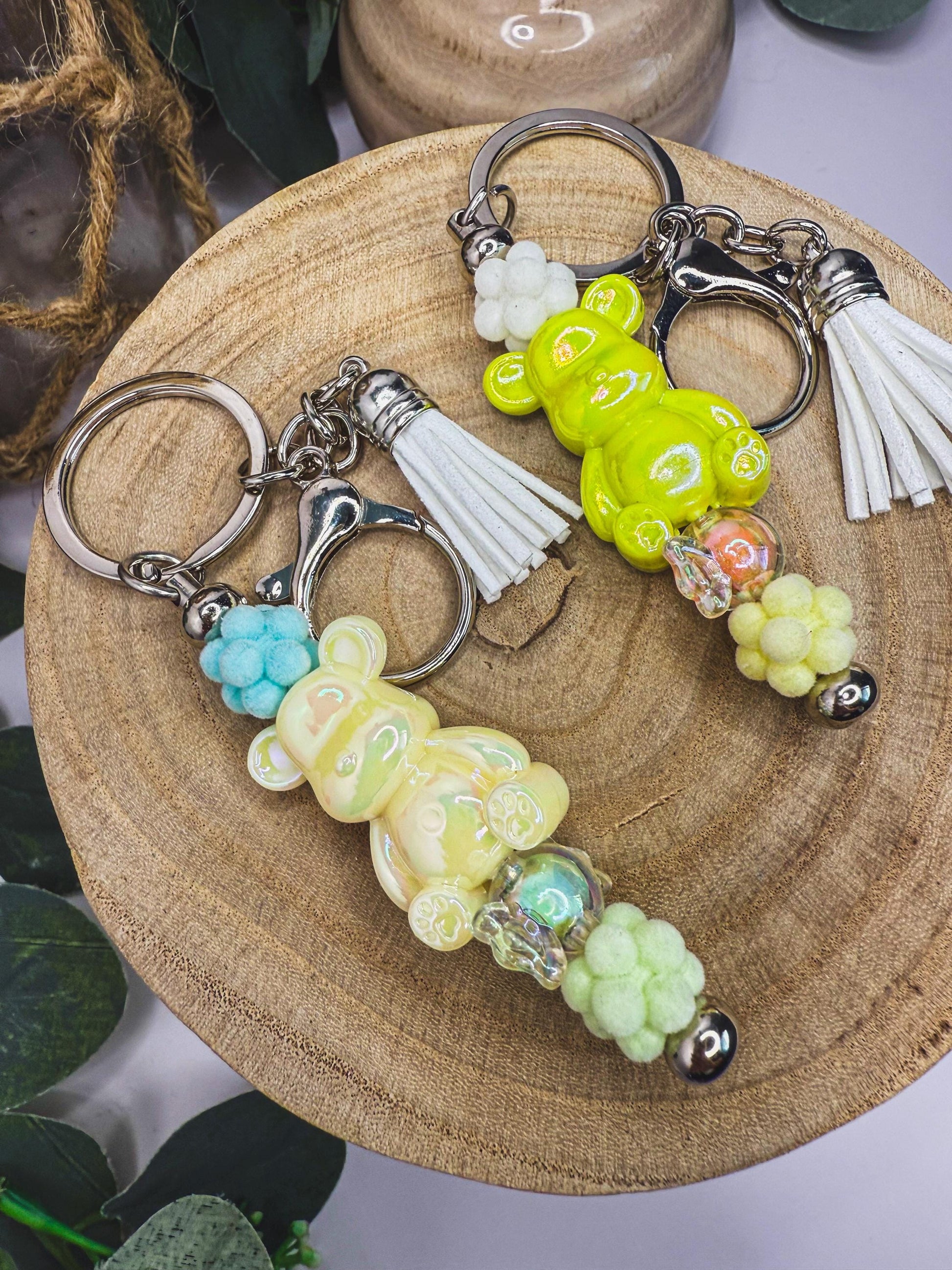two keychains with tassels and colorful beads, placed on a wooden surface.