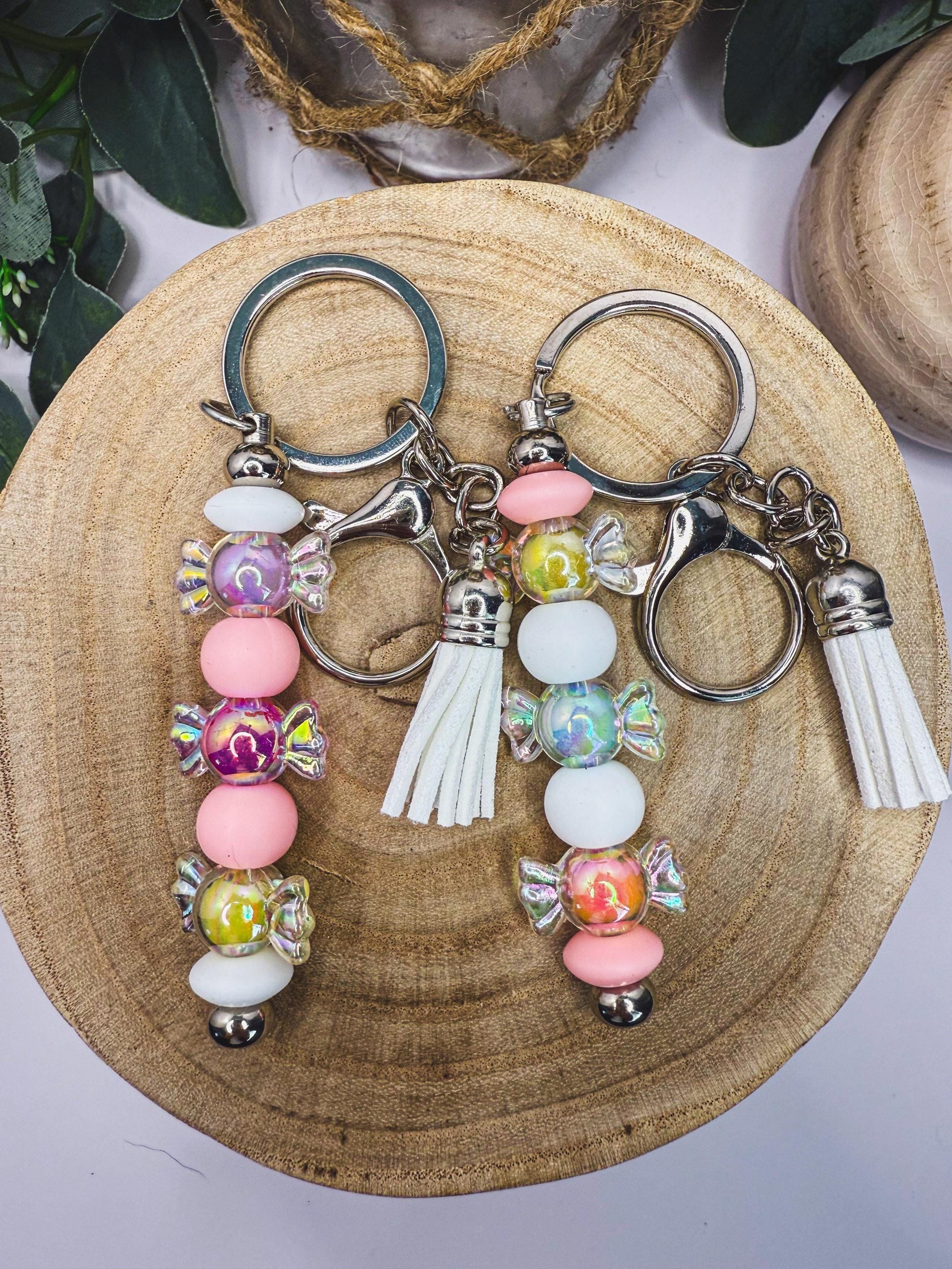 A pair of colorful keychains with candy-like beads and tassels, placed on a wooden surface.