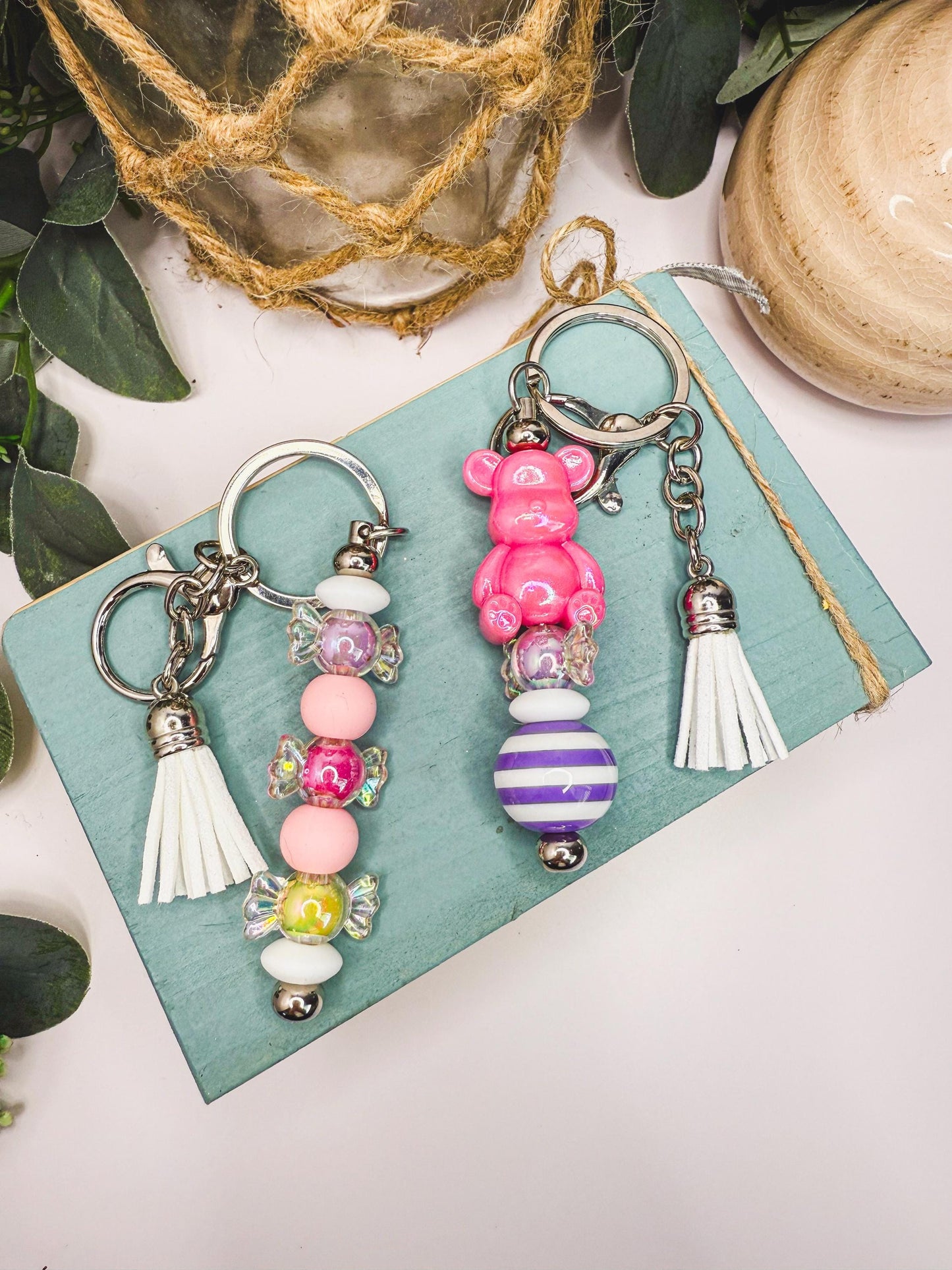 two colorful keychains with various beads and tassels, placed on a wooden surface.
