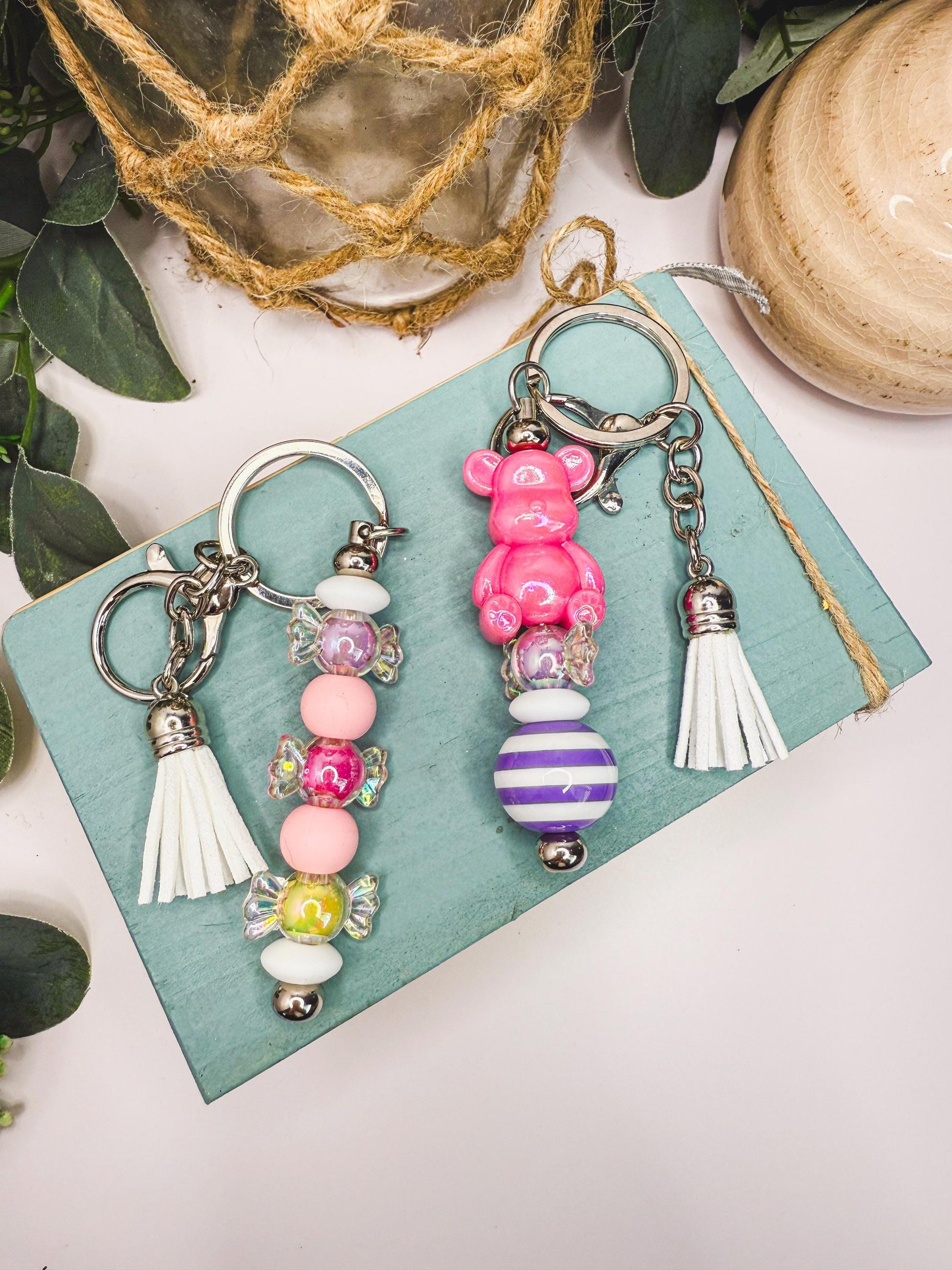 two colorful keychains with various beads and tassels, placed on a wooden surface.